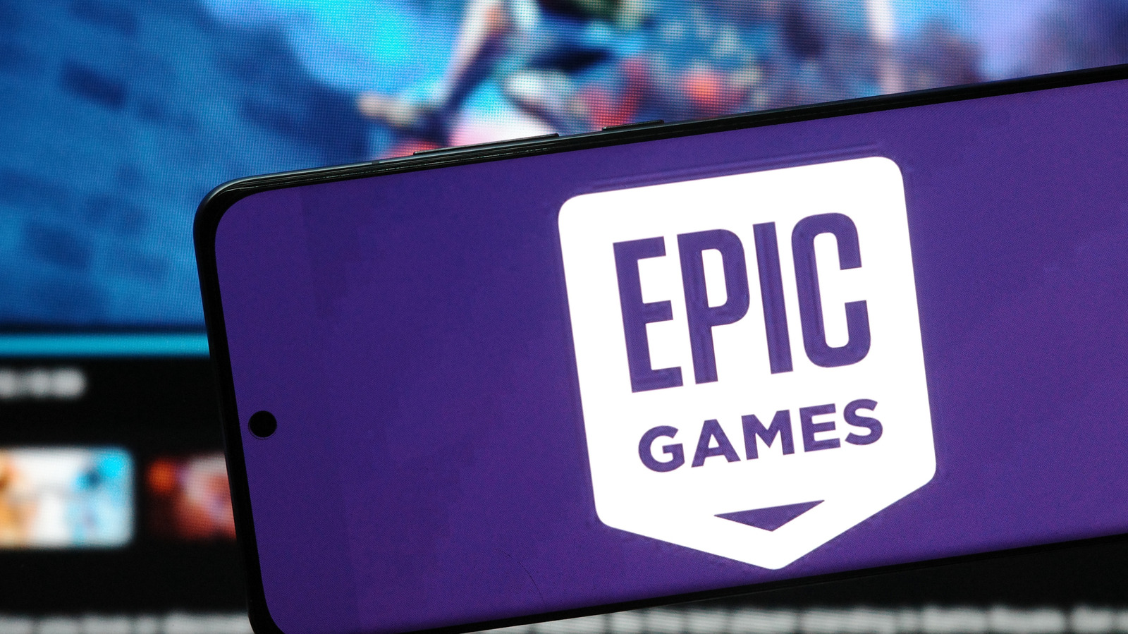 A smartphone showing the Epic Games logo on a purple backdrop, in front of the company's website